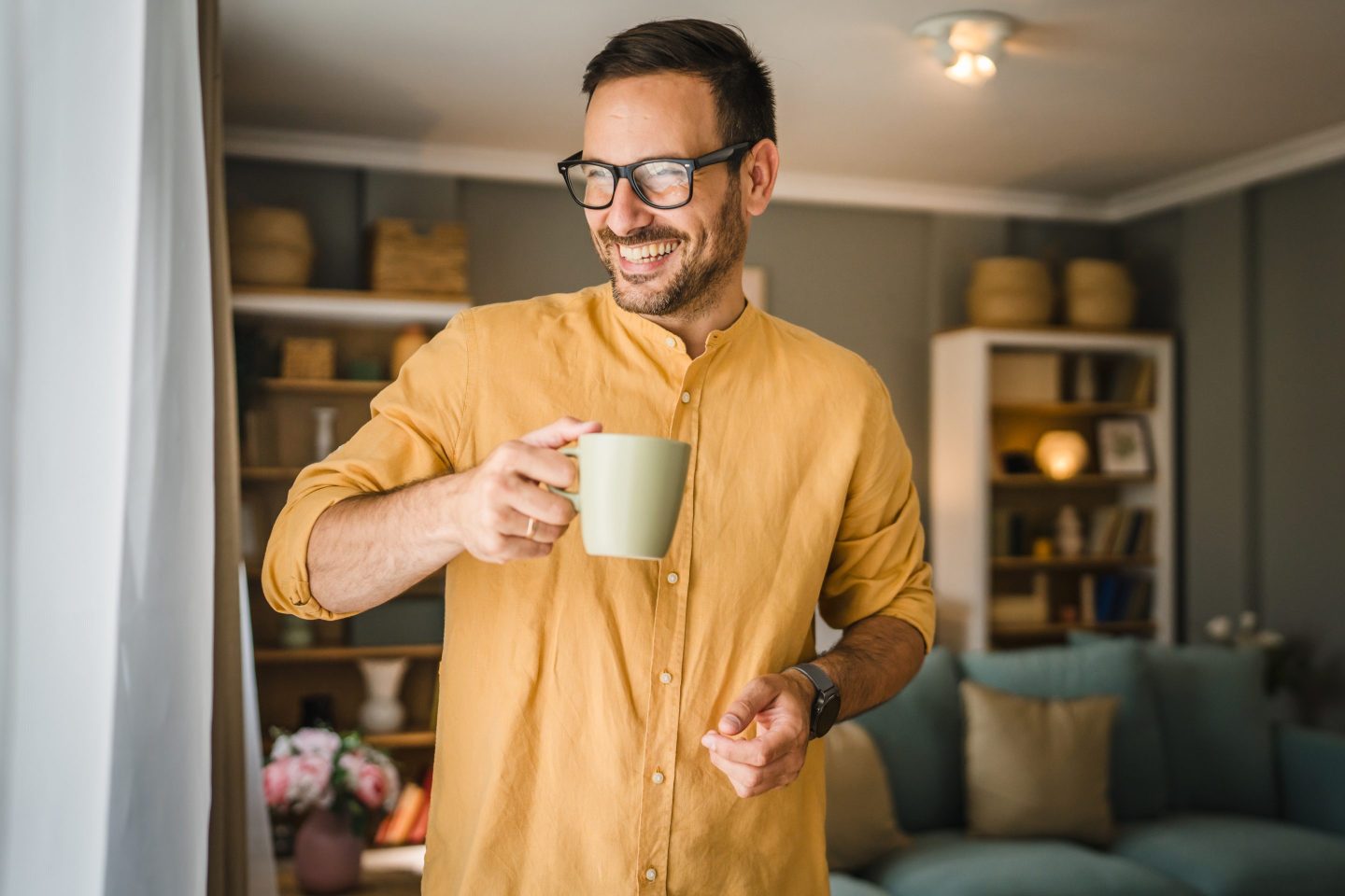 One young caucasian man having cup of coffee while standing at home wearing shirt in morning real people copy space